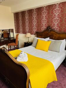 a bedroom with a large bed with a yellow blanket at Crown Hotel Brackley in Brackley