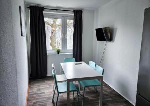 ein Esszimmer mit einem Tisch, Stühlen und einem Fenster in der Unterkunft Cozy apartments in Halle in Nietleben