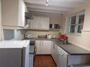 una pequeña cocina con armarios blancos y fregadero en Two Bedroomed House near Newark & Grantham, 