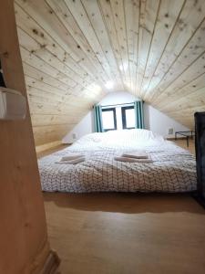 a large bed in a room with a wooden ceiling at Tiny House Stefana with garden in Transylvania 