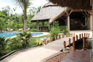 ein Holzsteg, der zu einem Resort mit Schwimmbad führt in der Unterkunft AXKAN PALENQUE, ALBERCAS, GASTRONOMIA MAR y TIERRA & TRAVEL AGENCY in Palenque
