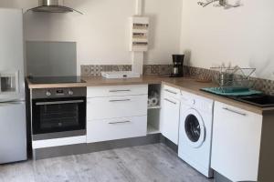 a kitchen with white cabinets and a washer and dryer at Les Dentelles du Ventoux - Gîte avec Piscine in Aubignan