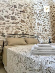a bed with towels on it with a stone wall at Arcaroli Borgo Vico "Exclusive" in Vico del Gargano