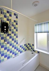 La salle de bains est pourvue d'une baignoire et d'un mur carrelé. dans l'établissement 26 Pier Avenue, à Southwold