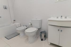 a white bathroom with a toilet and a sink at Departamentos Patagonia in Ushuaia
