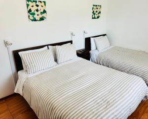 two beds in a room with white walls at Hostal Almares in Pichilemu