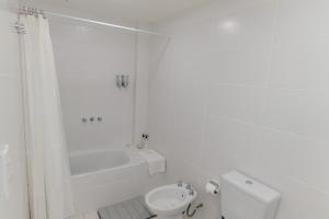 a white bathroom with a toilet and a bath tub at Departamentos Patagonia in Ushuaia