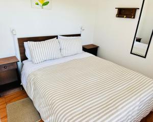 a bedroom with a bed with a striped comforter and a mirror at Hostal Almares in Pichilemu