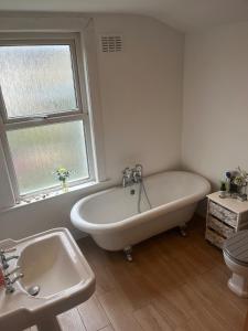 a bathroom with a tub and a sink and a window at Peaceful London Retreat in London