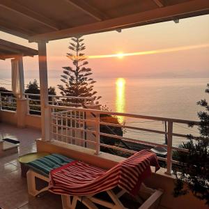 a balcony with a view of the ocean at sunset at Atena Mare Sea View in Perama
