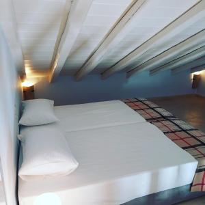 een bed met witte lakens en kussens in een kamer bij Vivi's Apartments Loft in Spetses