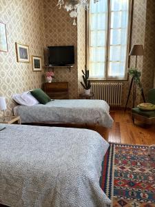 a room with two beds and a tv on the wall at B&B Chiara in San Sebastiano Curone