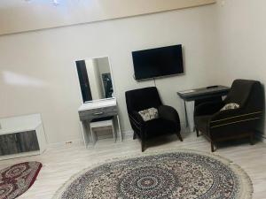 a living room with two chairs and a television at ObodHotel in Dushanbe