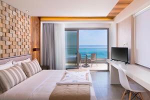 a bedroom with a bed and a desk and a television at Aegean Infinity Deluxe in Limenaria