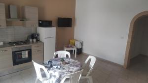 cocina con mesa, sillas blancas y nevera en Lino's house, en Adrano