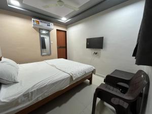 SihorHOTEL HARE KRISHNA的一间带床、椅子和电视的卧室