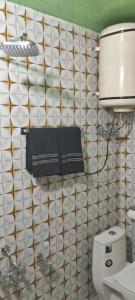 baño con aseo y pared de azulejos blancos en Conifer view guest house, en Tangmarg