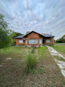 a brick house with a yard in front of it at Casa del lago in Termas de Río Hondo