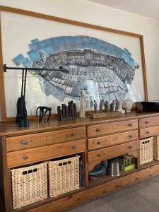 a wooden dresser with a large painting on the wall at Maison de famille in Chaponost