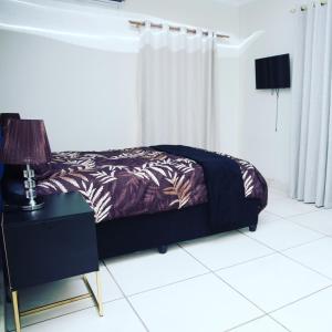 a bedroom with a bed and a table with a lamp at AZALEA LODGE in Midrand
