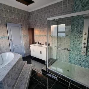 uma casa de banho com um chuveiro, um lavatório e uma banheira em AZALEA LODGE em Midrand