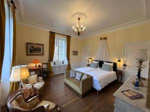 a bedroom with a bed and a chair and a chandelier at Chateau du Gue aux Biches in Bagnoles de l'Orne