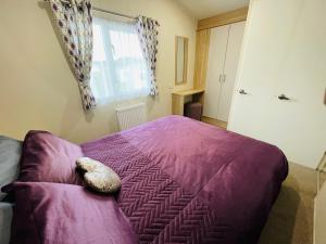 a bedroom with a purple bed with a teddy bear on it at Water Sky Getaways 3-bedroom caravans at Durdle Door in Wareham