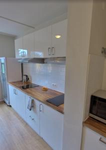 a kitchen with white cabinets and a wooden counter top at BusinessHotel Am Peetzsee Grünheide 