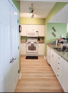 a kitchen with white cabinets and green walls at Your Ultimate Beachfront retreat! Brand New Flooring!! in Panama City Beach