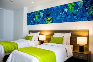 two beds in a room with a painting on the wall at Torca Hotel in Cali