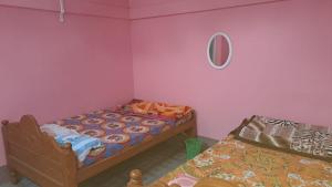 1 dormitorio con 2 camas y espejo en la pared en MANAS RAY HOMESTAY, en Jyoti Gaon