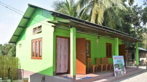 a green and colorful house with a sign in front at MANAS RAY HOMESTAY in Jyoti Gaon