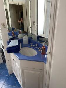 uma casa de banho com um lavatório azul e um espelho. em 2 pièces au centre de Monaco em Monte Carlo