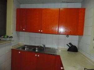 a kitchen with red cabinets and a sink at Holiday homes in Dubai