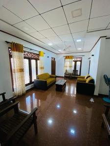 a large living room with couches and chairs and windows at Villa Binna in Galle