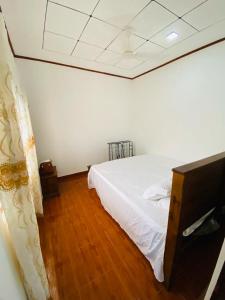 a bedroom with a white bed and a wooden floor at Villa Binna in Galle