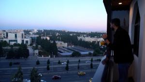 a man standing in a window looking out at a parking lot at Red Carpet Suites in Amman