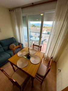 a dining room table and chairs with a view of a living room at Apartamento El Faro playa Nules in Castellón de la Plana