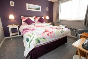 a bedroom with a large bed with a floral bedspread at Fonthill Bed and Breakfast Nairn in Nairn