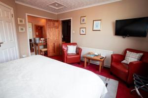 a bedroom with a bed and two chairs and a flat screen tv at Fonthill Bed and Breakfast Nairn in Nairn