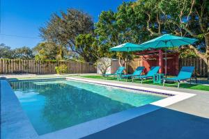 a swimming pool with blue chairs and umbrellas at Holiday Home 4 Bedrooms with Private Pool near HardRock Casino in Hollywood