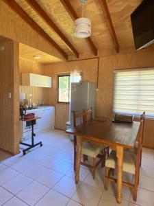 a kitchen with a wooden table and a refrigerator at Cabañas Mili in Panguipulli