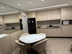 a kitchen with a white table and chairs and a counter at Flat próximo ao Shopping Campo Grande in Campo Grande