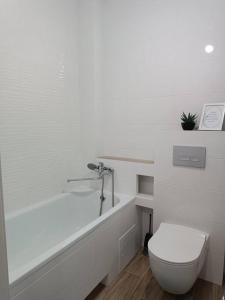 La salle de bains blanche est pourvue de toilettes et d'une baignoire. dans l'établissement Apartament in Ialoveni la 5 km de Chisinau, à Ialoveni