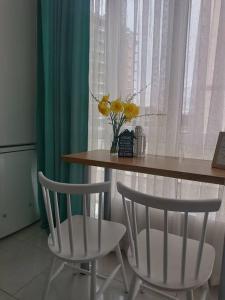 stół z 2 krzesłami i waza z żółtymi kwiatami w obiekcie Apartament in Ialoveni la 5 km de Chisinau w mieście Ialoveni