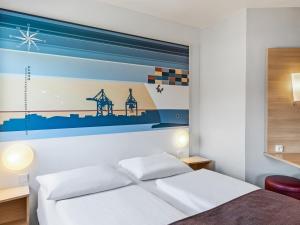 a bedroom with a bed with a painting on the wall at B&B Hotel Hamburg-Altona in Hamburg