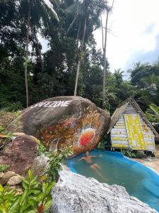 a large rock with graffiti on it next to a swimming pool at SZ Samui Glamping in Ban Sa Ket