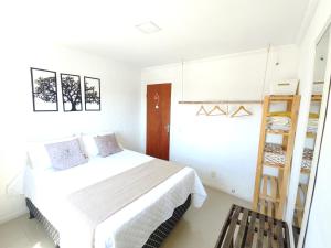 a white bedroom with a bed and a ladder at Linda casa em ossos 70 m da praia in Búzios