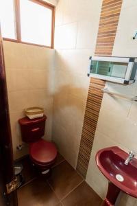 a bathroom with a red toilet and a sink at Casita Linda Baños in Baños