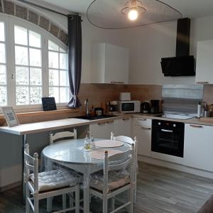 uma cozinha com uma mesa e algumas cadeiras e uma mesa e uma cozinha em Cottage chaleureux à 25 mn de la côte de granit rose em Bégard
